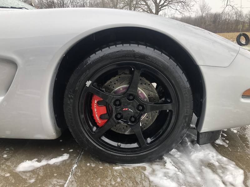 Mobile car detailing in Kannapolis, NC: Close-up of a silver Corvette's glossy black wheel, red brake caliper, and shined tire after a wash