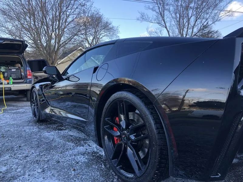 Mobile car detailing in Tega Cay, SC: Black C7 Corvette Stingray with glossy paint reflecting the sky after a detail