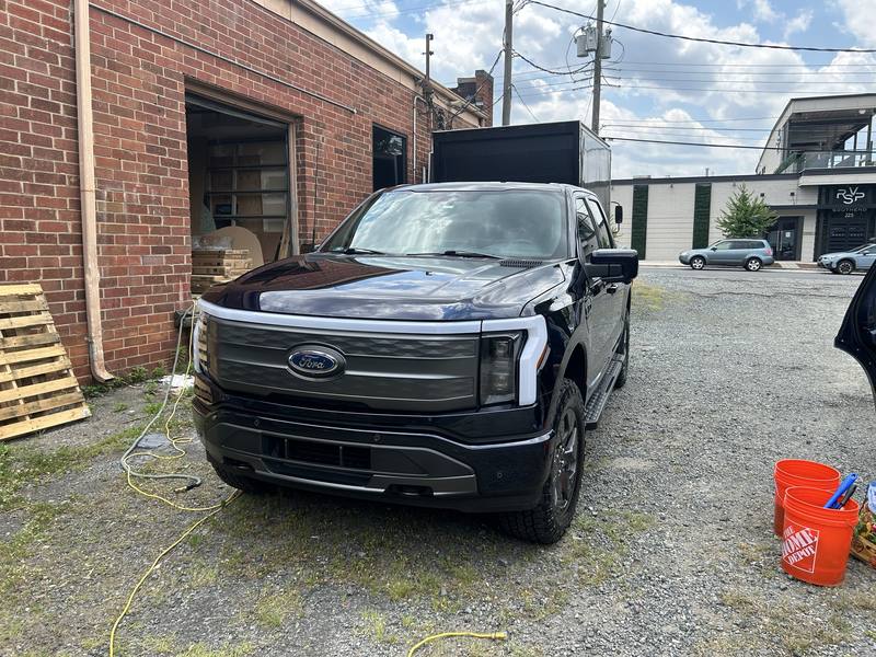 Mobile car detailing in Charlotte, NC: Dark blue Ford F-150 Lightning after a mobile wash, parked beside a brick building