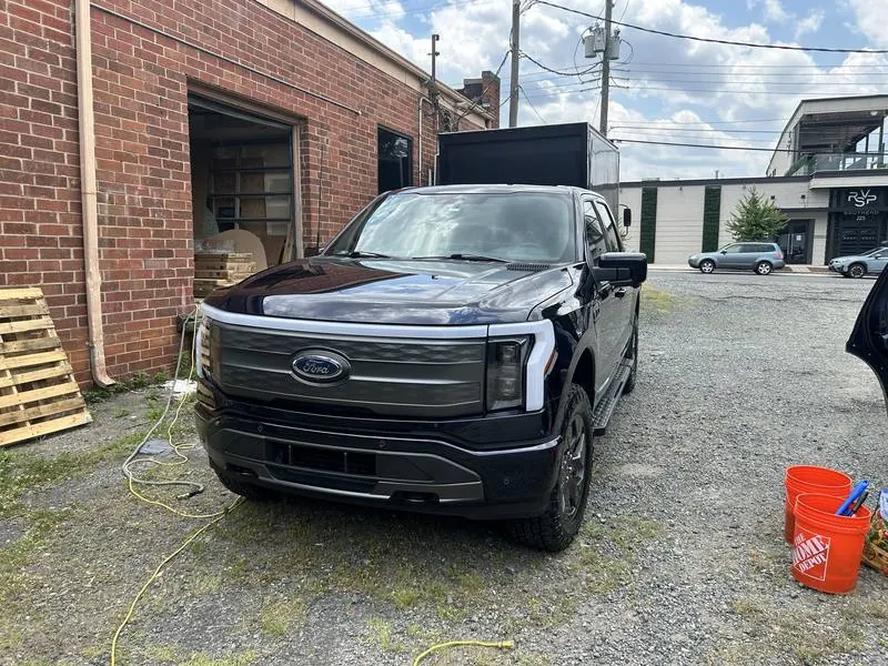 Premium mobile car detailing in Raleigh, NC: Dark blue Ford F-150 Lightning after a mobile wash, parked beside a brick building
