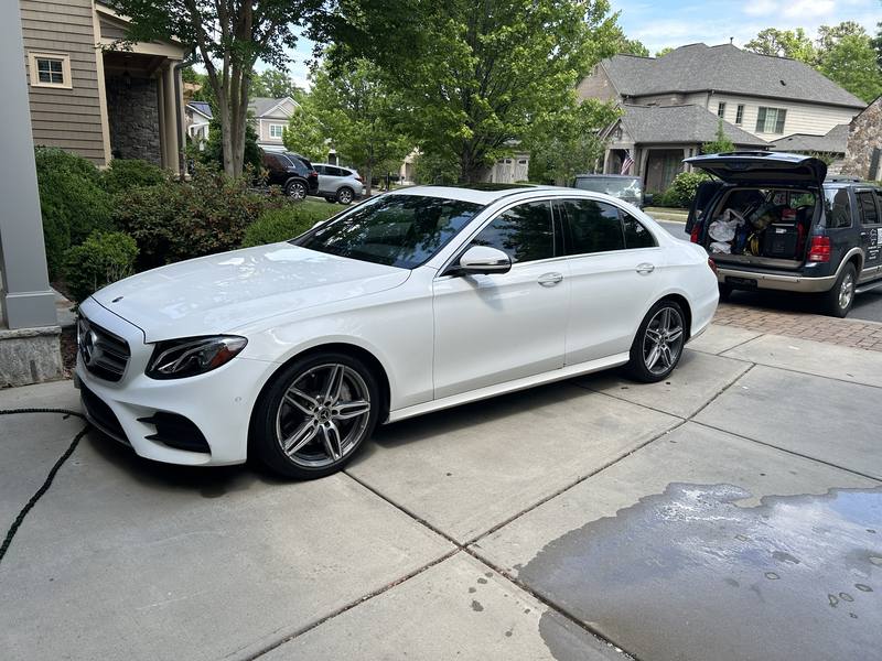 Car window tint in Charlotte, NC: White Mercedes-Benz E-Class sedan with tinted rear windows in a driveway