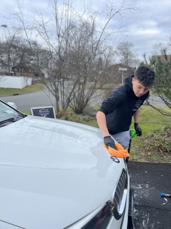 Mobile wash and wax in Charlotte, NC: Detailer wiping down the hood of a white BMW with a microfiber towel