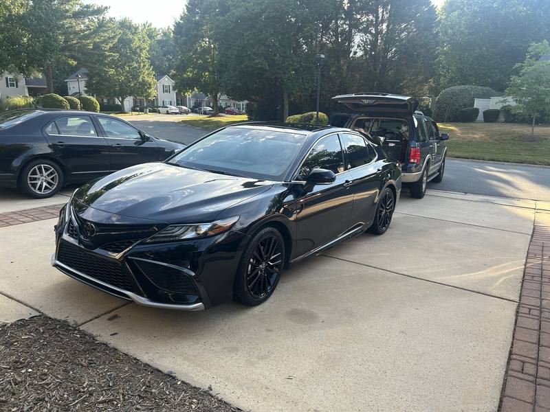 Car window tint in Charlotte, NC: Black Toyota Camry with dark tinted windows and black wheels in a driveway